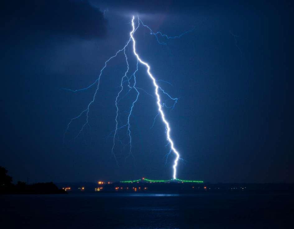 Lightning striking over a dark cityscape at night.